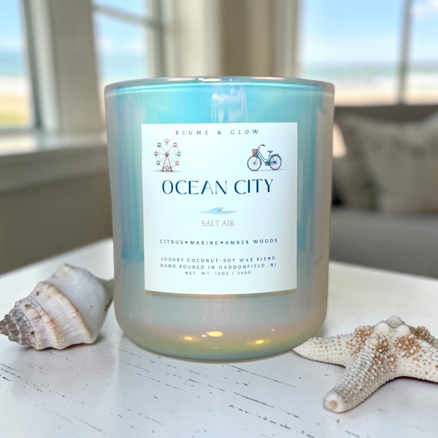 Ocean City coastal citrus candle by Blume & Glow burning on a wooden surface with orange and grapefruit fragrance