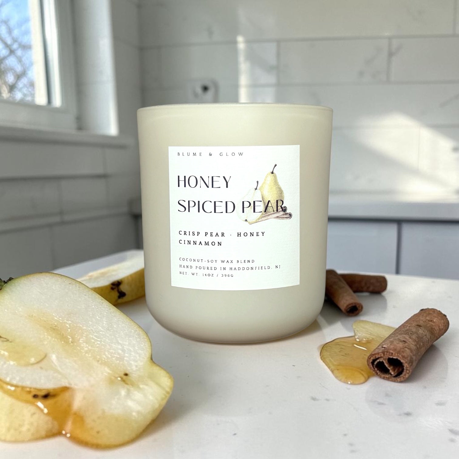 Honey Spiced Pear candle by Blume & Glow styled on a kitchen counter with sliced pears, honey drizzle, cinnamon sticks, and cozy fall décor.