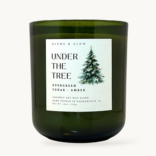 Under the Tree evergreen cedar and amber Christmas candle by Blume & Glow with wooden wick and coconut-soy wax blend in transluscent green vessel