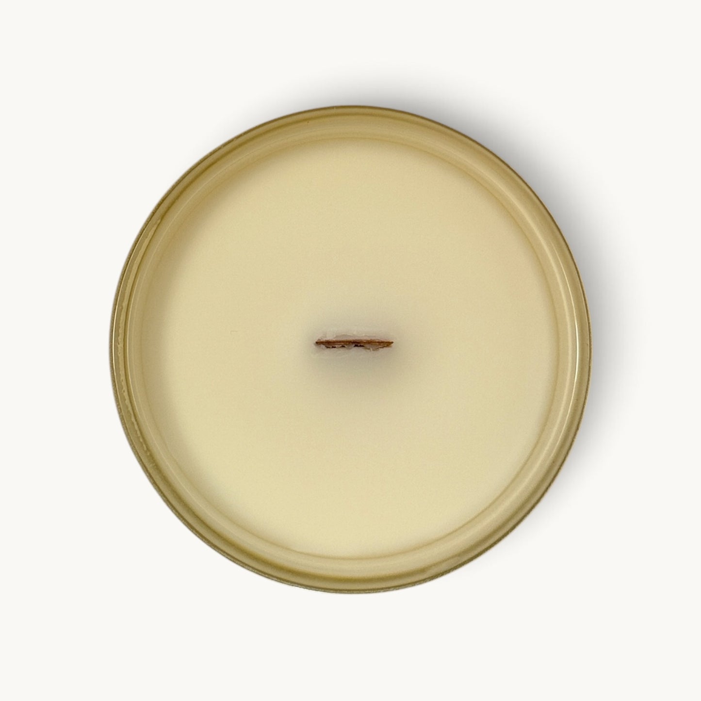 Top-down view of a single-wick coconut soy candle in a round glass jar with a warm beige/cream wax and a matching beige rim, centered on a white background.