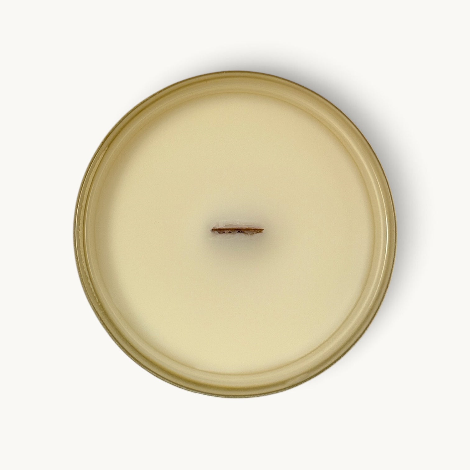 Top-down view of a single-wick coconut soy candle in a round glass jar with a warm beige/cream wax and a matching beige rim, centered on a white background.